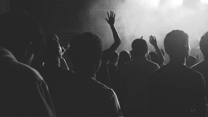 Concert crowd with raised hands under bright stage lights
