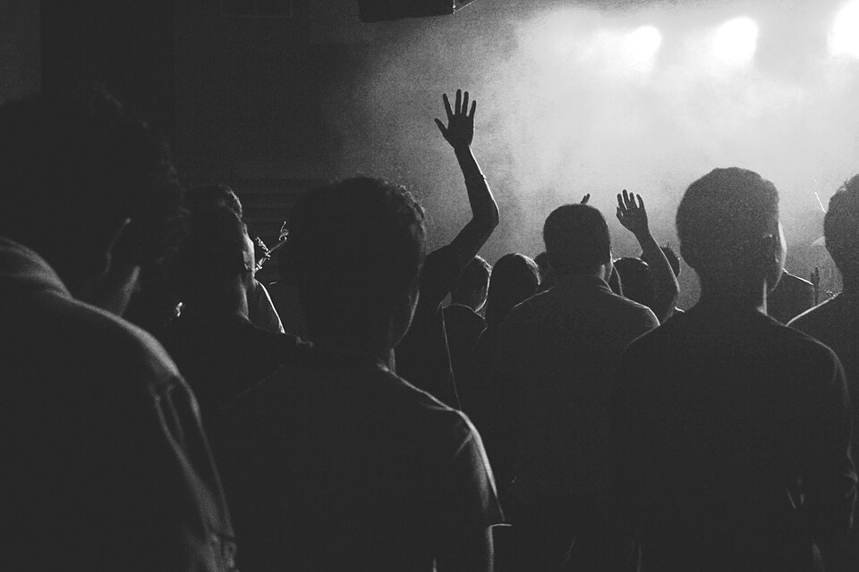 Concert crowd with raised hands under bright stage lights