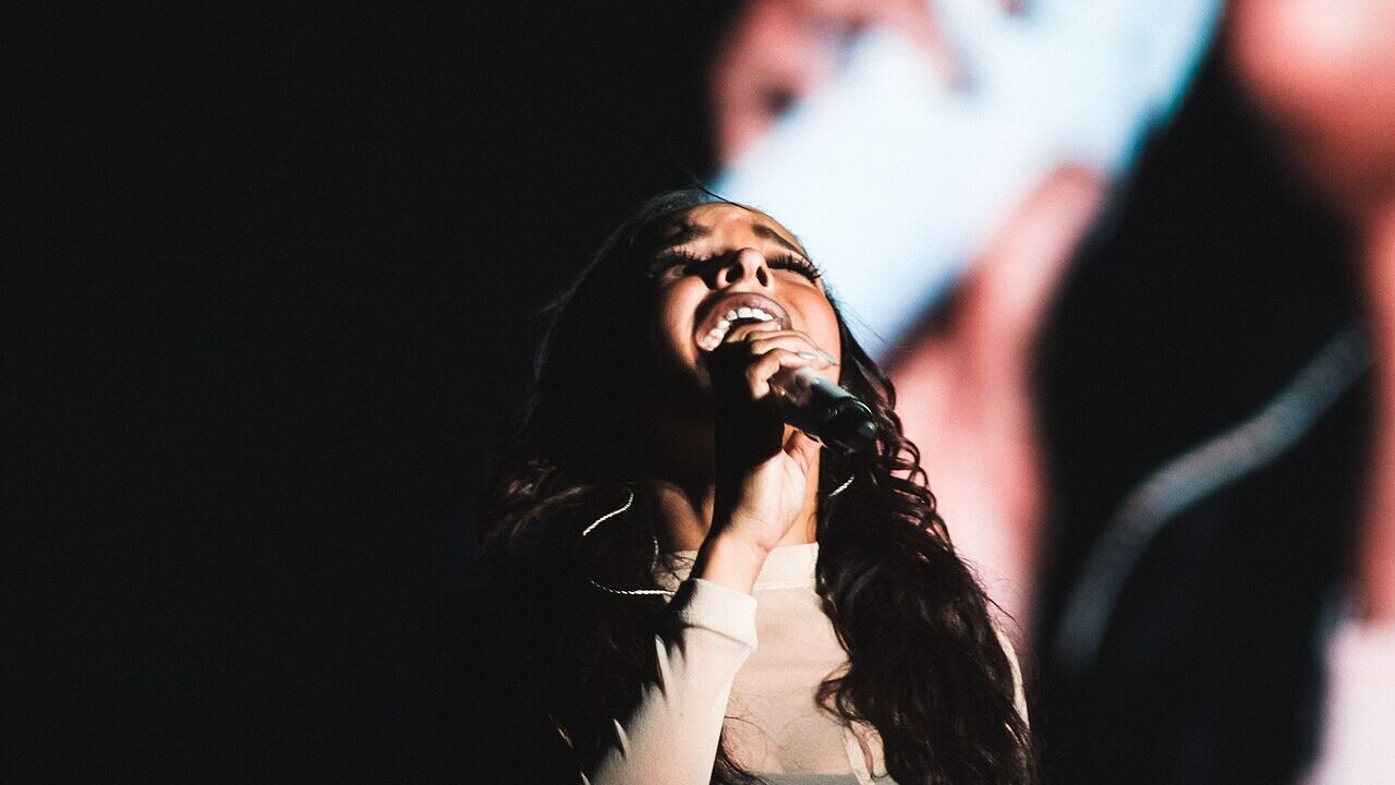 Tinashe singing into a microphone during a live performance
