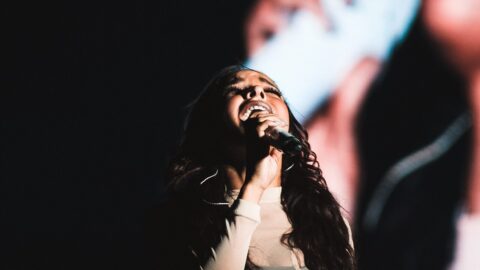 Tinashe singing into a microphone during a live performance